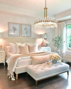 a bedroom with white furniture and chandelier hanging from it's ceiling, along with pictures on the wall