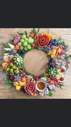 a wreath made out of fruits and vegetables on a wooden table with a cup of coffee