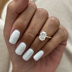 a woman's hand with white manicured nails and a ring on her finger