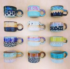 many different colored coffee mugs are lined up on a table top with one cup in the middle