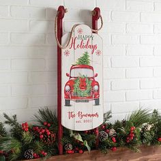 a wooden sign hanging on the side of a brick wall next to evergreens and pine cones