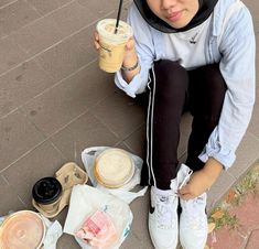 a woman sitting on the ground holding a drink