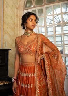 Editor's Note Introducing an exquisite rust heavily hand-embroidered lehenga set, paired with our signature printed organza-based dupatta. The intricate hand embroidery, featuring jaal, motifs, and highlighting borders, adds a touch of opulence and elegance to the ensemble. The rust hue exudes warmth and sophistication. Step into any special occasion with confidence, draped in this captivating rust lehenga set that effortlessly combines traditional craftsmanship with contemporary flair. Color: O Burnt Orange Saree, Wedding Anarkali, Rust Indian Outfit, Burnt Orange Lehenga, Rust Anarkali, Traditional Orange Embroidered Lehenga, Rust Lehenga, Rust Orange Saree, Orange Embroidered Party Lehenga