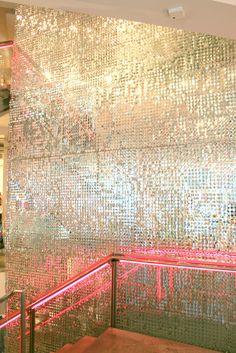 a large metal wall with red lights in the corner and stairs leading up to it