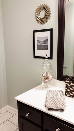 a bathroom with a sink, mirror and pictures on the wall