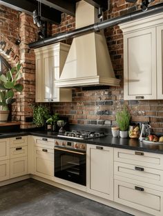 a kitchen with white cabinets and black counter tops next to a brick wall that has exposed piping