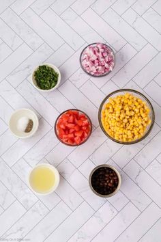 bowls filled with different types of food on top of a white tiled counter next to small bowls