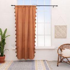 an orange curtain hangs in front of a window with a potted plant next to it