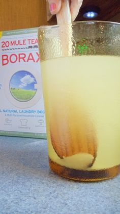 a glass filled with liquid sitting on top of a counter next to a box of borax