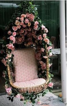 a chair made out of wicker with flowers on the back and seat is covered in pink roses