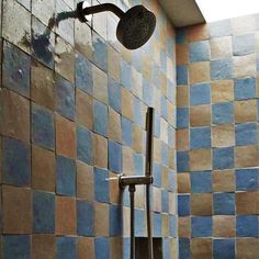 a shower head and hand held shower faucet in a tiled bathroom with blue tiles on the walls