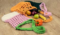 there is a crocheted bag with fruits and vegetables on the floor next to it