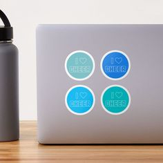 a laptop computer sitting on top of a wooden table next to a bottle and cup