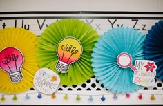 three paper fans with light bulbs on them hanging from a bulletin board in a classroom