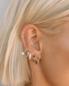 a woman with blonde hair wearing three different ear piercings on her left side and one in the middle