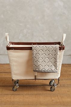 two laundry bags sitting on top of a wooden floor next to a white bag with wheels