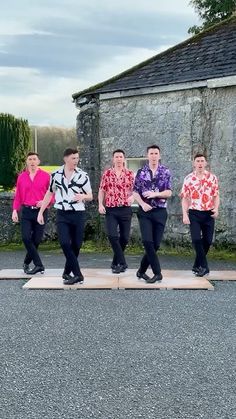 five men in colorful shirts are standing on wooden planks