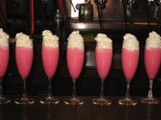 five glasses filled with pink liquid and whipped cream