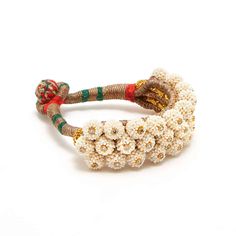 Inspired by a pair of pearl cuffs owned by the Maharani of Balunda... A hand stitched, tightly woven silk cuff studded with tiny Pearls highlighted by tiny twinkling White Topaz.- Natural Pearls.- Natural White Topaz.- Size 7 with a silk bobble closure. Celebrating the Unique Style of Traditional Village Jewelry with a Contemporary Twist... We Draw Our Inspiration from Rajasthani Tribal Design. ‘Balunda Baubles’ are Carefully Crafted by the Village Goldsmith and the Pieces Have an Appealing Orga Luxury Brass Jewelry With Meenakari, Luxury Traditional Jewelry With Wooden Beads, Luxury Traditional Meenakari Bangle, Elegant Handwork Jewelry For Festive Occasions, Elegant Handwork Jewelry For Festivals, Elegant Handwork Jewelry For Wedding, White Pearl Bangle Bracelet For Festive Occasions, White Elegant Ceremonial Bangle, Elegant White Ceremonial Bangle