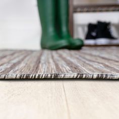 a pair of green rain boots sitting on top of a wooden floor next to a black boot