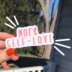 someone holding up a sticker that says more self - love