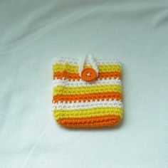 an orange, white and yellow crocheted cell phone case with a button on it