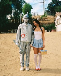 a woman standing next to a statue of a man in a suit and hat on the beach