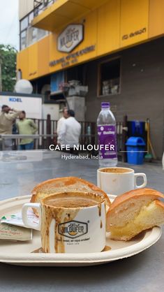 a plate that has some bread on it and two cups with coffee in front of it