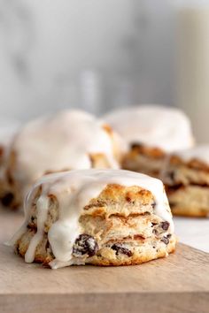 some cookies with icing and chocolate chips on a cutting board next to a glass of milk