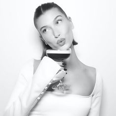 a woman holding a glass of wine making a funny face