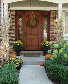 the front door is decorated with pumpkins and flowers