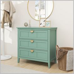 a green dresser sitting in front of a mirror on top of a wooden floor next to a wicker basket