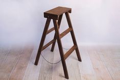 a wooden step stool sitting on top of a hard wood floor next to a white wall