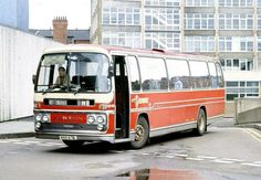 a red and white bus driving down a street next to tall buildings in the background