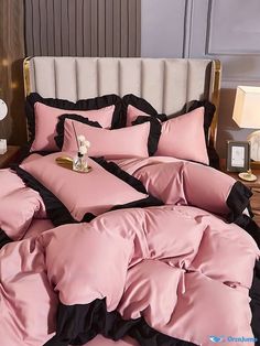 a bed with pink and black comforters on top of it next to a night stand