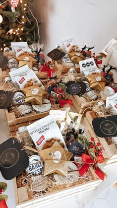 a table topped with lots of boxes filled with different types of food and decorations next to a christmas tree