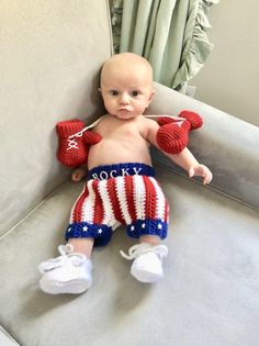 a baby sitting on top of a couch wearing red, white and blue knitted shorts