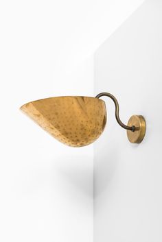 a wall mounted brass plated hook on the side of a white wall with a curved handle