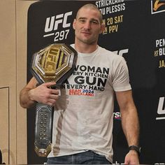 a man standing in front of a microphone holding a wrestling belt