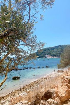 the beach is surrounded by rocks and trees