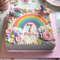 a birthday cake decorated with flowers and a rainbow