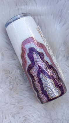 a pink, purple and white tumbler sitting on top of a fur covered floor