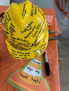 a hard hat with writing on it sitting on top of a table next to a marker