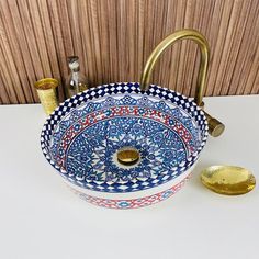 a blue and white sink sitting on top of a counter next to a brass faucet