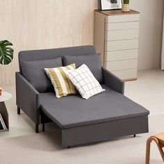 a grey couch with pillows on top of it next to a coffee table and chair