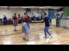 two people dancing on a wooden floor in front of an audience at a dance class