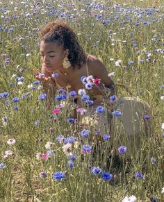 a woman kneeling down in a field of flowers