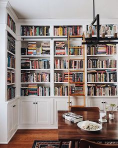 a dining room table in front of a bookcase filled with books