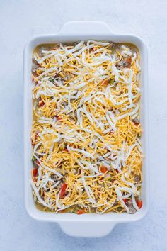 a casserole dish with cheese and vegetables in it on a white table top