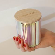 a woman's hand holding a metallic container with red nail polish